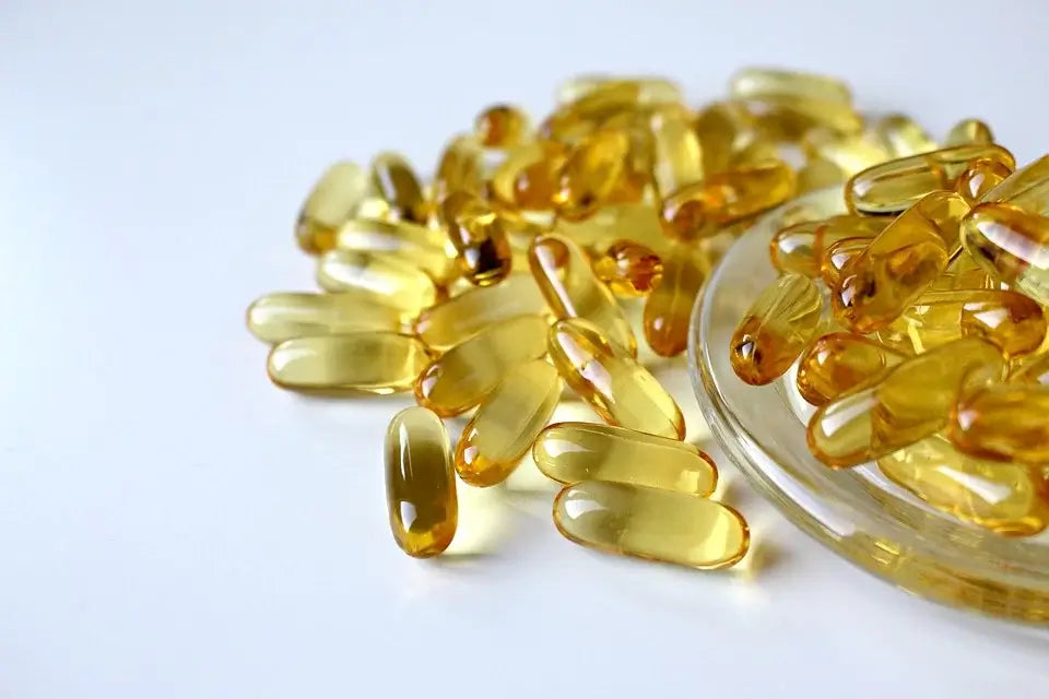 An assortment of yellow, translucent gel capsules, known as some of the best supplements, is spread on a white surface.