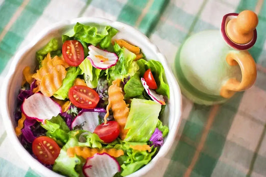 A fresh salad in a white bowl containing lettuce, cherry tomatoes, radish slices, and crinkle-cut carrot pieces.