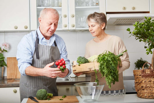 An elderly man and woman prepare vegetables together in a kitchen, combating metabolic syndrome.