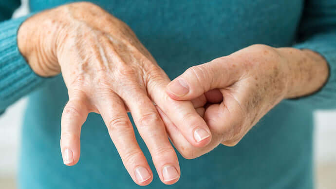 Close-up of a pair of elderly hands with visibly wrinkled and freckled skin.
