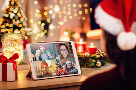 Person in a Santa hat using a tablet for a video call with four friends, all wearing festive hats.
