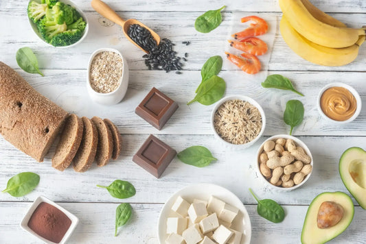An assortment of magnesium-rich foods displayed on a wooden surface, including bread, broccoli, oats, black beans, shrimp
