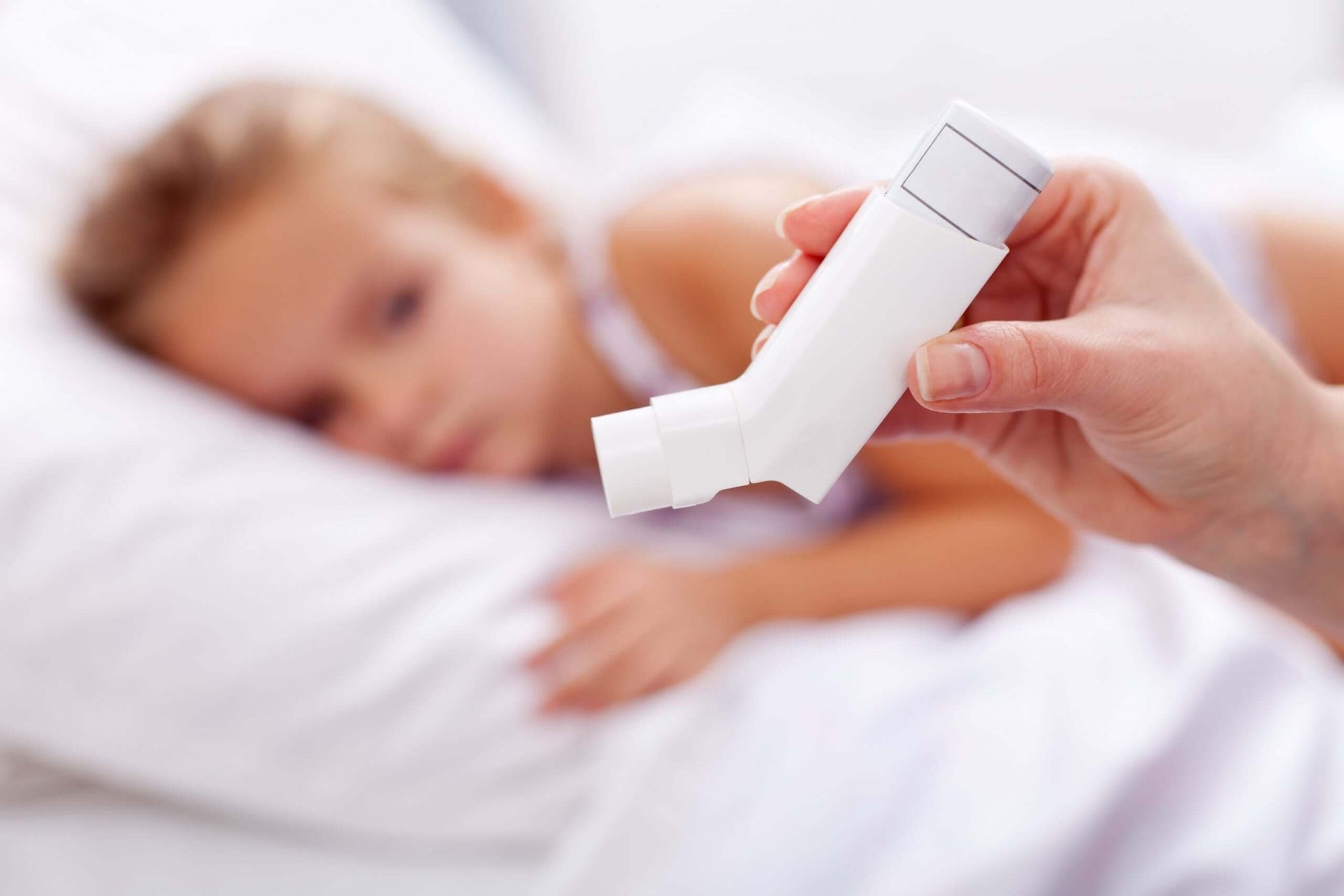 A close-up of a hand holding an inhaler in the foreground.
