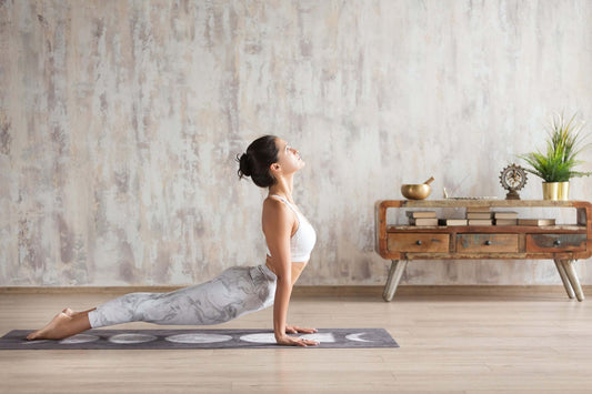 A woman practices yoga in a spacious, minimalist room with wooden flooring.