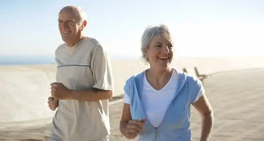 An older man and woman, both advocates for Omega-3, are jogging together outdoors on a sunny day.