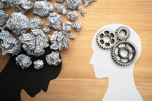 A conceptual image showing two paper cutout silhouettes of heads on a wooden surface.