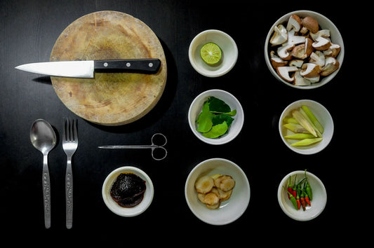 A top-down view of cooking ingredients and utensils arranged neatly on a dark surface.