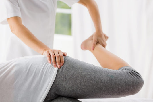 A physical therapist manipulates a patient's leg during a therapy session.