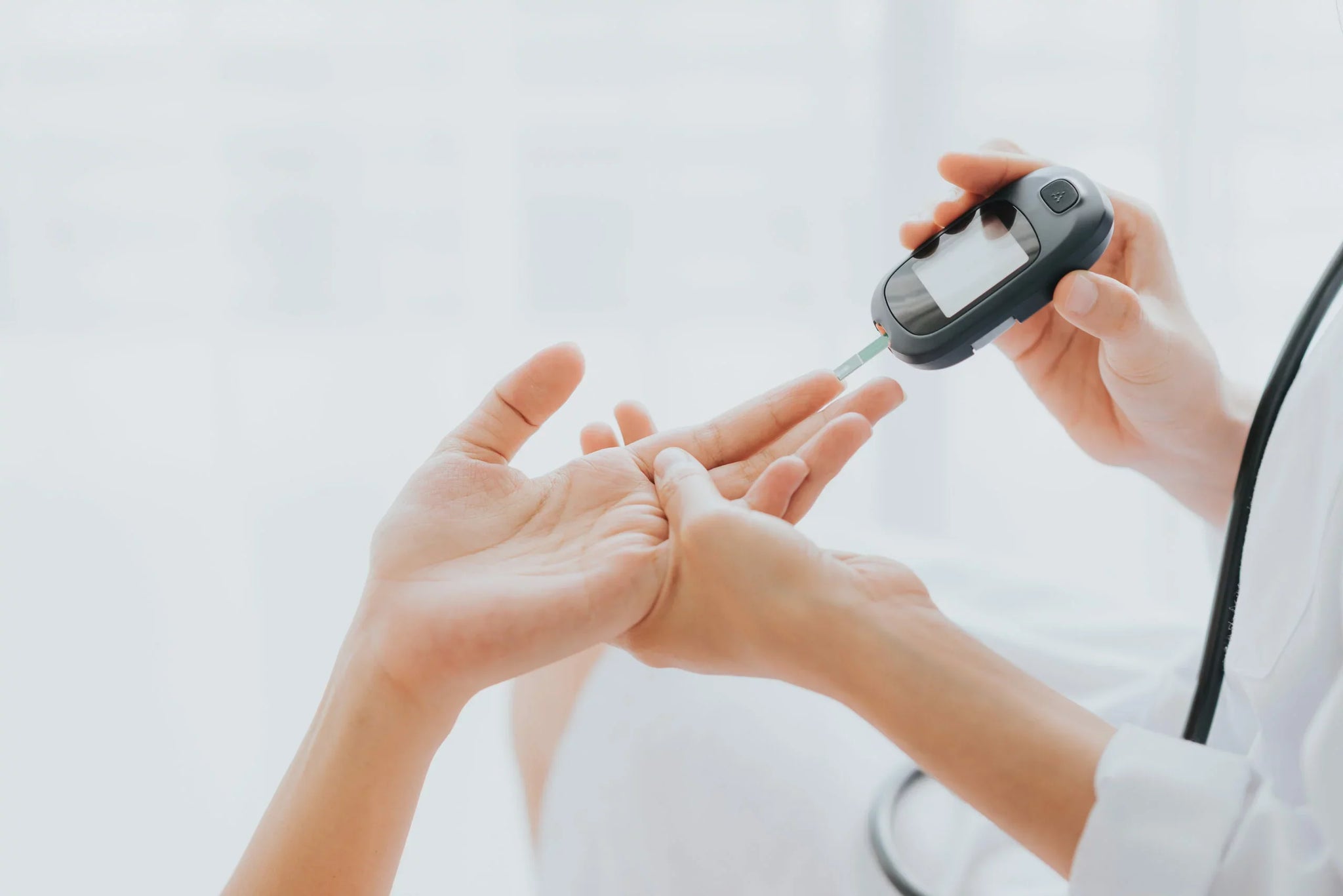 A healthcare professional uses a glucose meter to check blood sugar levels by pricking a patient's finger.