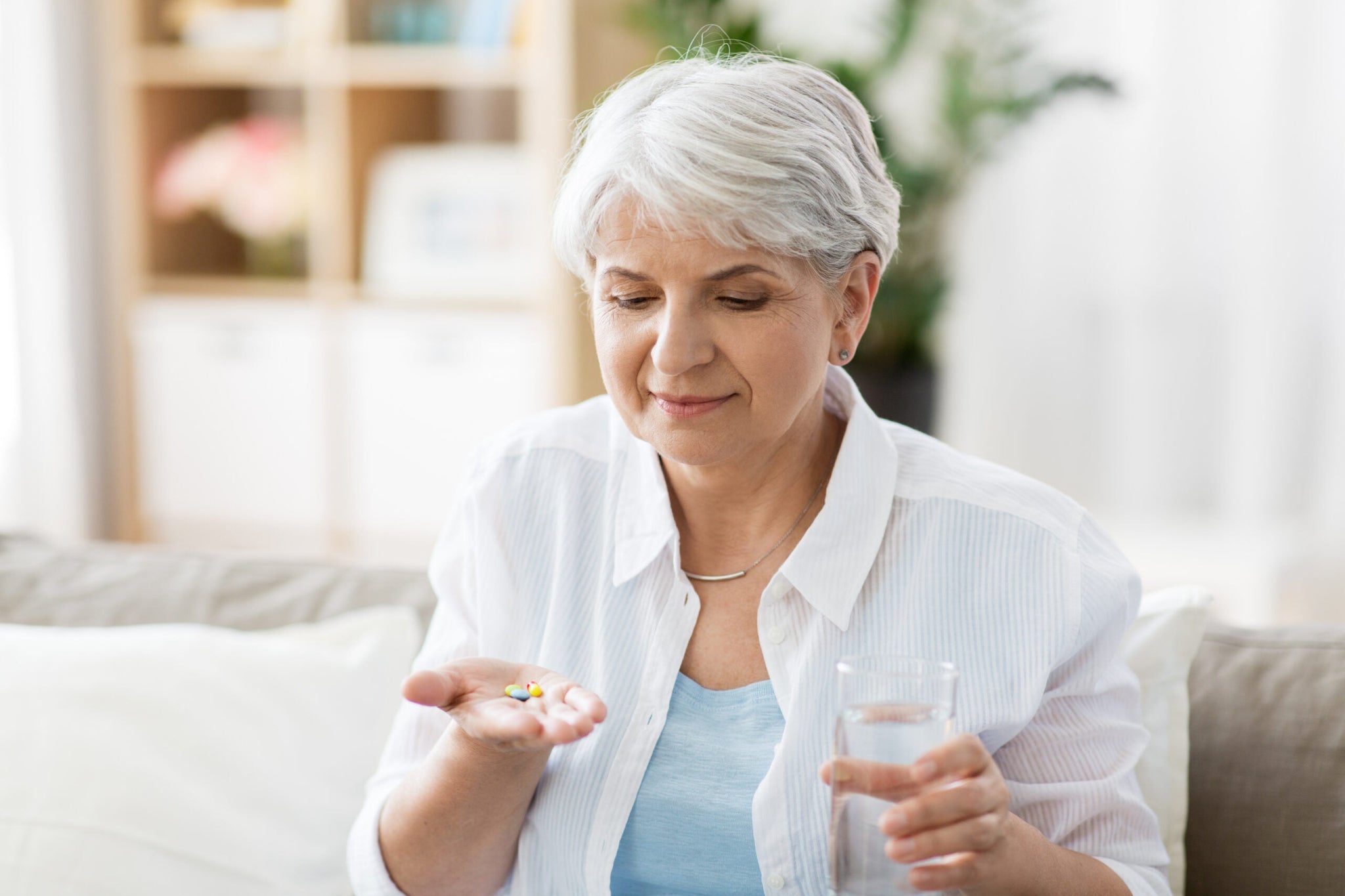An older woman with short gray hair is sitting on a couch.