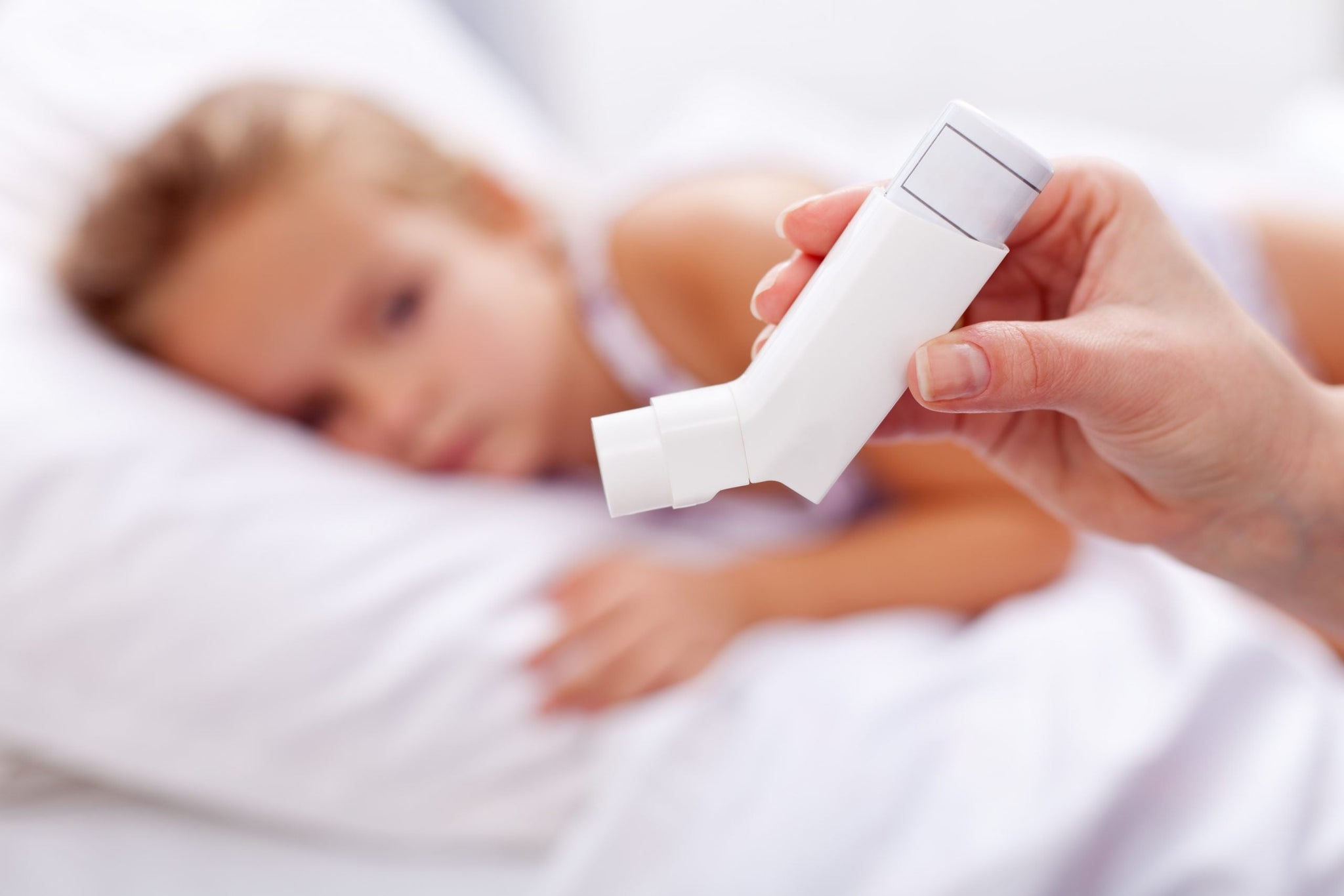 A close-up of a hand holding an inhaler in the foreground.