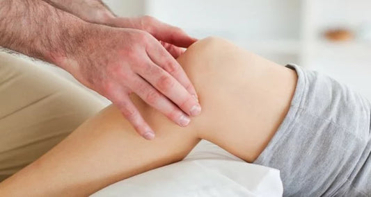 A close-up of a person's hands gently massaging a knee, perhaps suggesting to start using cold for arthritis pain relief.
