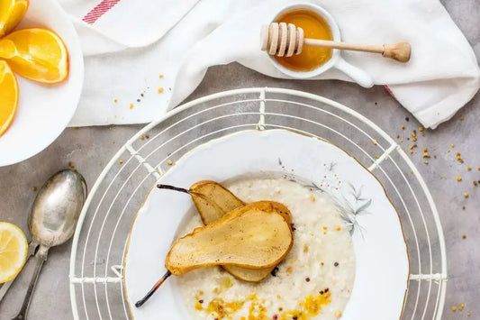 A plate of porridge topped with roasted pear halves sits on a white tablecloth.