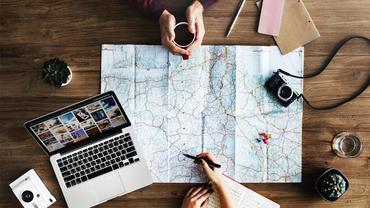 A wooden table with a large map covering most of it serves as a hub for holiday travel tips.