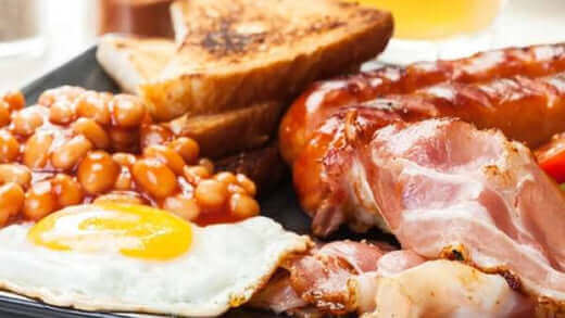 List of Foods That Cause Inflammation: Breakfast plate with beans, bacon, toast, and fried egg.