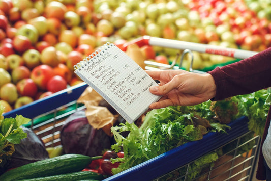 A person holding a handwritten shopping list in a grocery store.