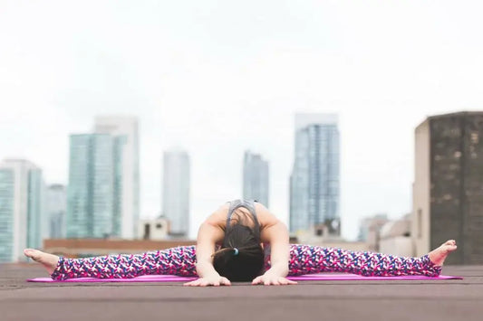 Person performing a wide-angle seated forward bend yoga pose on a pink mat.